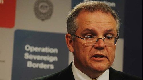Australian Immigration Minister Scott Morrison stands in front of an Operation Sovereign Borders sign